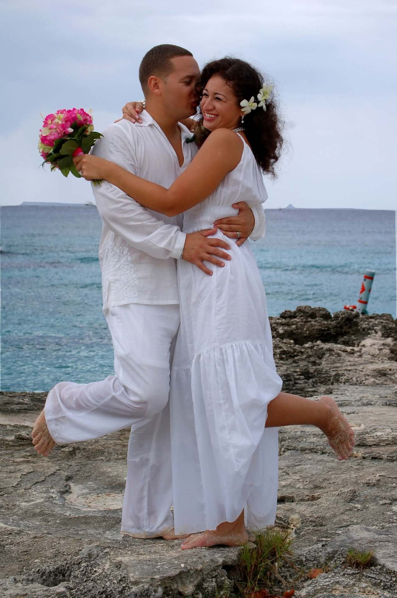 Eric and Haydee Rodriguez on their wedding day, barefoot on the beach in white.